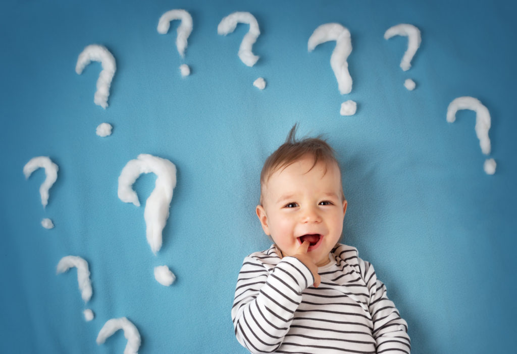 funny little boy lying on blue blanket with lots of question marks